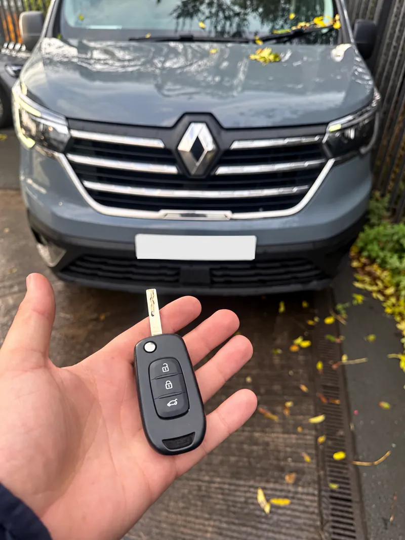 Grey Renault Trafic van with a Renault remote flip key held in front of it, number plate obscured