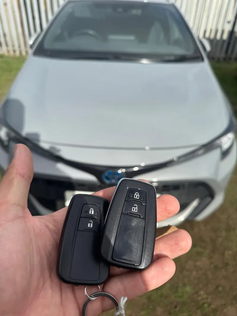 Silver Toyota Corolla with two black Toyota smart keys held in front of it